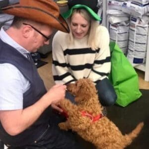 A man and woman in hats with a brown curly-haired puppy