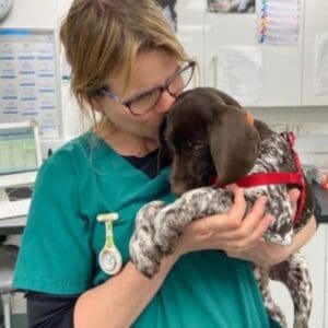Emma the vet nurse cuddling and kissing a brown and white puppy