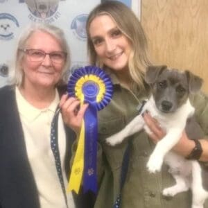 Two ladies with their puppy and a rosette